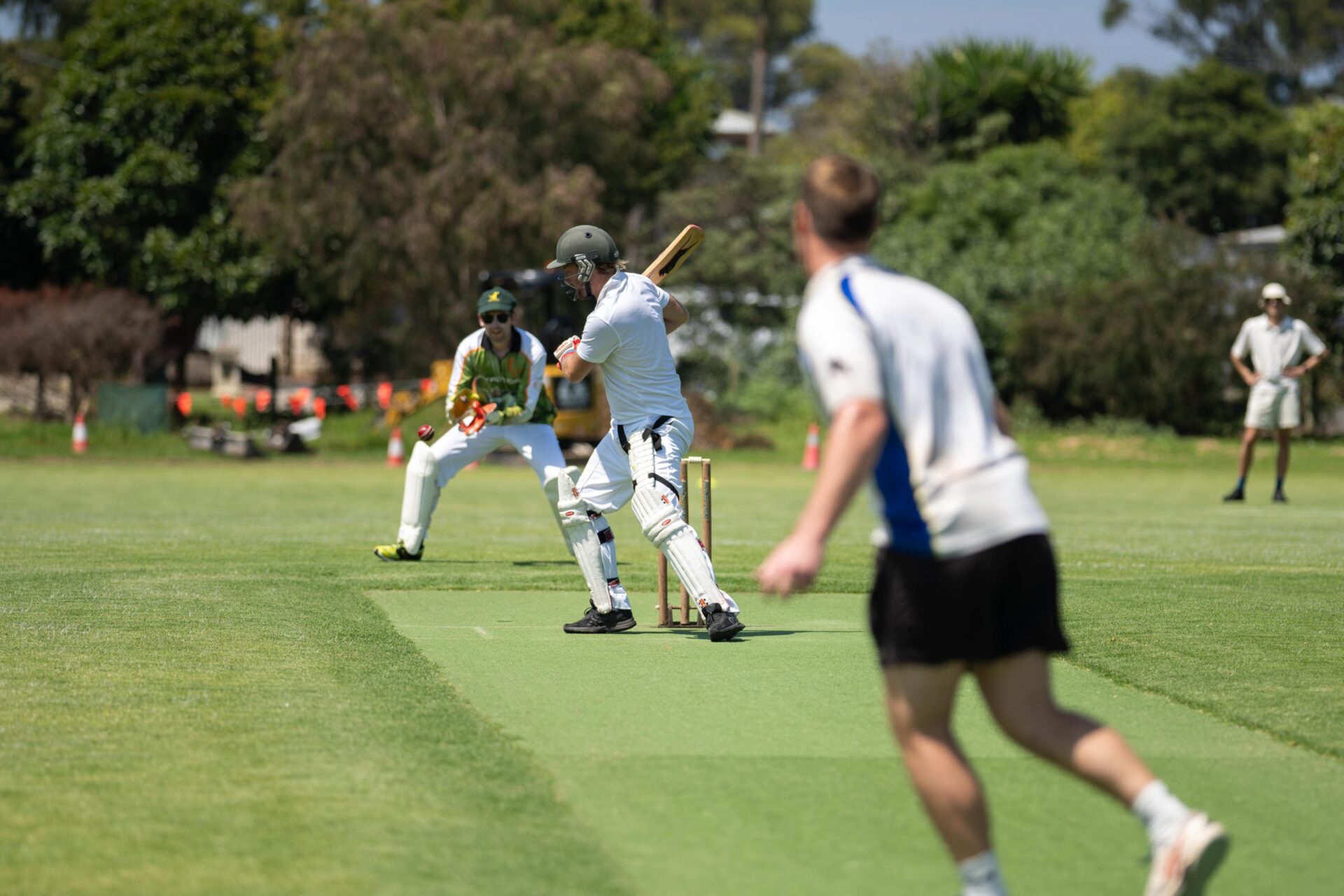 a local cricket match being played on a green cricket oval in summer in australia